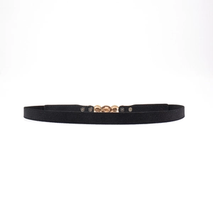 Détail d'une ceinture élastique noire avec une boucle en métal doré à double anneau