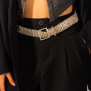 Détail d'une ceinture dorée luxueuse sertie de strass sur un blazer noir élégant