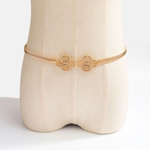 Détail de la chaîne de taille élastique dorée avec boucle florale double sur un mannequin