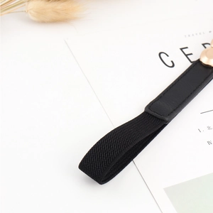 Détail d'une ceinture élastique noire avec boucle métallique dorée et finitions en cuir