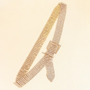Détail de la ceinture à plusieurs rangées de strass dorés avec boucle carrée sertie