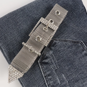 Vue détaillée d'une ceinture en maille argentée avec boucle en strass sur denim