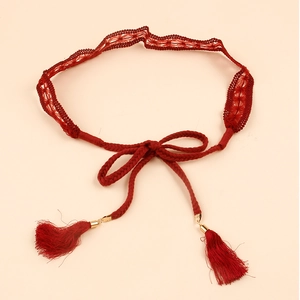 Detailed macro view of red lace weaving and ethnic tassel pendants on the slim belt