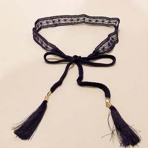 Close-up of deep purple lace belt with golden metal caps and elegant silk tassels