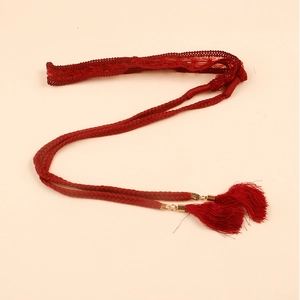 Detailed macro view of dark red lace woven belt with elegant tassels and golden metal clips