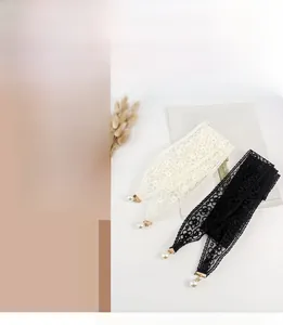 Détail de ceintures en dentelle élégantes en noir et blanc avec pendentifs perles