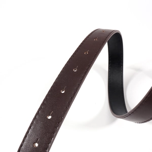 Détail d'une ceinture en cuir marron foncé avec grain litchi et coutures soignées