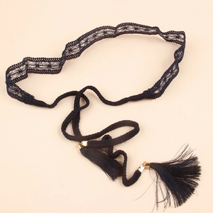 Detail of bohemian black lace belt with woven rope tassels and gold metal accents
