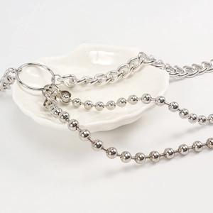 Détail d'une chaîne de taille argentée avec maille gourmette et perles métalliques