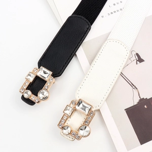 Close-up of elastic waist belts in black and white with rhinestone-encrusted gold buckles