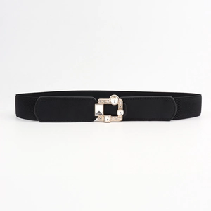 Close-up of women's elastic belt featuring a golden buckle with geometric rhinestones