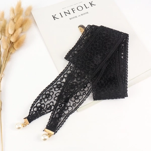 Détail d'une ceinture en dentelle florale noire avec d'élégantes perles blanches