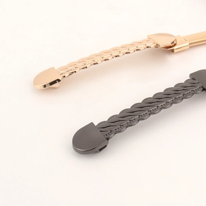 Detail of elegant wave chain waist belt with capsule buckle in gold and gunmetal