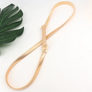 Close-up of golden elastic metal waist chain with textured buckle and spring link detail
