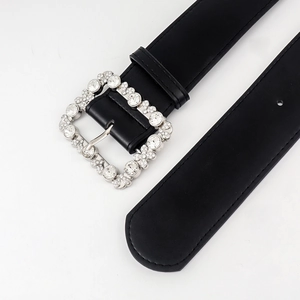 Detail of black leather belt featuring a large square buckle with shimmering rhinestones