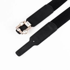 Close-up of golden metal buckle with rhinestones on a black elastic waist belt