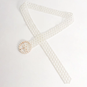 Close-up of elegant woven pearl belt with a round gold buckle for evening dresses