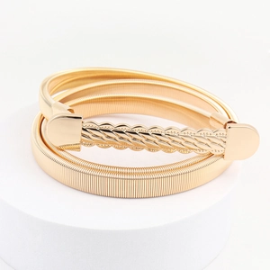 Women's gold elastic metal belt with stylish wave pattern buckle on white podium