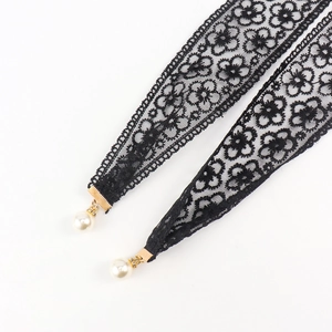 Détail d'une ceinture en dentelle noire avec motifs floraux et pendentif en perles fines