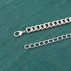 Détail de la ceinture chaîne en métal argenté avec fermoir mousqueton et maillons superposés