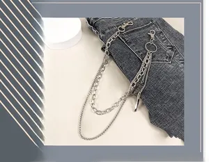 Detail of silver multi-layered punk style trousers chain with metal charms on dark denim