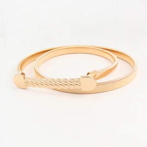 Detailed close-up of golden elastic metal spring belt with twisted knot buckle