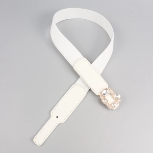 Detailed macro view of white elastic waist belt with rose gold rhinestone buckle