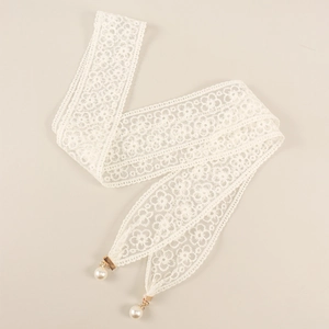 Détail de la ceinture en dentelle blanche avec motifs floraux et pompons en perles