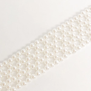 Detailed macro view of woven faux pearl belt with four-row hollow diamond mesh pattern