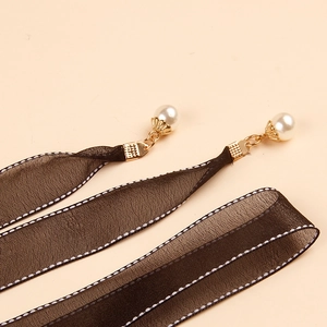 Detalle de cinta de encaje negro con bordes de punto blanco y colgante de perla elegante