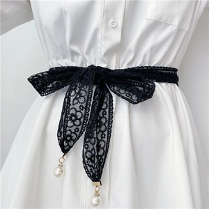 Détail de la ceinture en dentelle noire avec pendentifs perles blanches nouée en un nœud