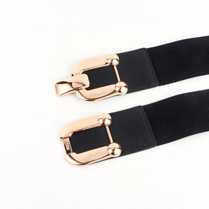 Close-up of black elastic wide belt with polished gold horseshoe buckle and faux leather trim