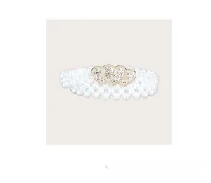 Dettaglio cintura in perle multistrato con tre fibbie a cuore con strass scintillanti