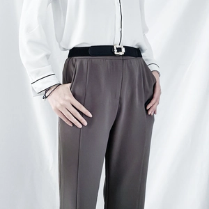 Close-up of black elastic belt featuring a sparkling rhinestone buckle on a white shirt