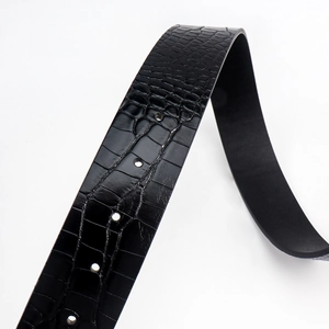 Close-up of black belt featuring embossed crocodile texture and smooth adjustment holes