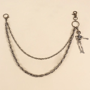 Détail de la chaîne de pantalon double en métal gris avec pendentif crâne et fermoirs mousquetons