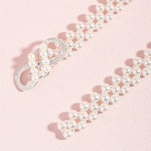 Détails d'une ceinture en perles avec boucle en argent infini et strass scintillants