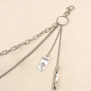 Detail of silver multilayered metal pants chain with engraved plaque and pendant charms