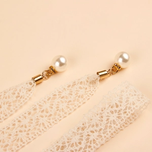 Detalle del cinturón de encaje crema con perla elegante y colgante de metal dorado