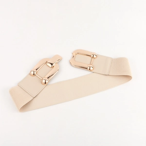 Detail of beige elastic waist belt with a golden geometric metal buckle for dresses