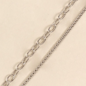 Close-up of punk style silver metal chains featuring oval links and braided rope patterns