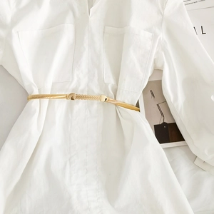 Detail of elegant gold snake chain elastic belt with decorative buckle on white shirt
