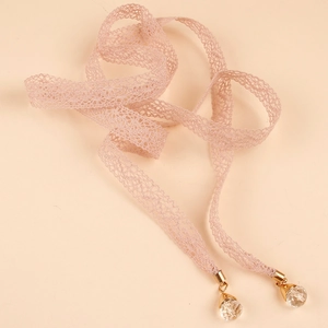 Detalle del cinturón de encaje rosa con herrajes dorados y colgantes de cristal brillante