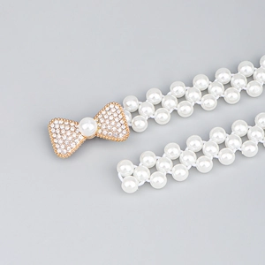 Détail d'une élégante ceinture de taille en perles double rangée avec boucle nœud doré