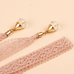 Detalle de cinturón de encaje rosa con colgantes de perlas y hebillas de metal dorado