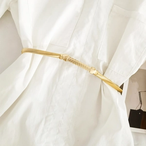 Close-up of golden elastic metal spring belt with twisted texture on a white shirt