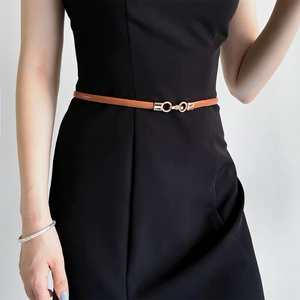 Close-up of brown leather belt with gold chain buckle on a black dress waist