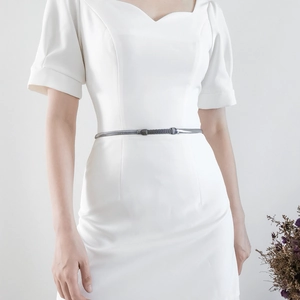 Close-up of a slim metallic gunmetal chain belt with a capsule buckle on a white dress