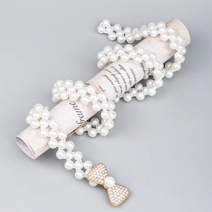 Chaîne de taille élégante en perles blanches avec boucle nœud en strass et métal doré