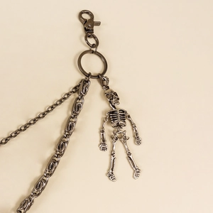 Détail d'une double chaîne de pantalon noir avec pendentif crâne et fermoir mousqueton